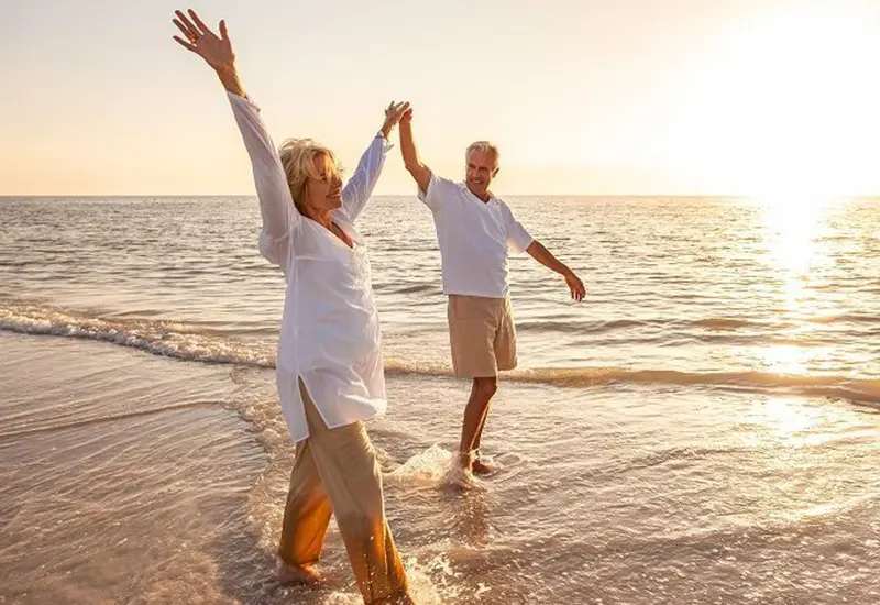 Couple joyfully walking hand-in-hand along the beach at sunset.
