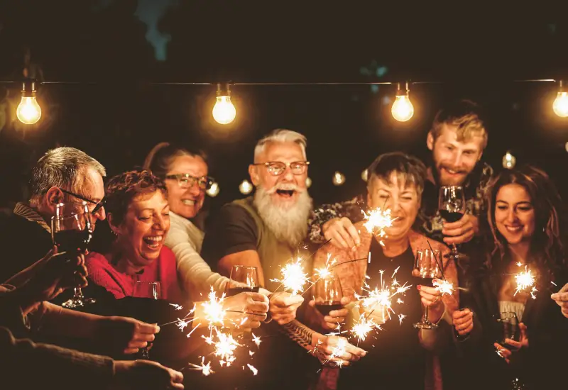 A joyful group celebrating with sparklers and smiles in a warm, festive atmosphere.